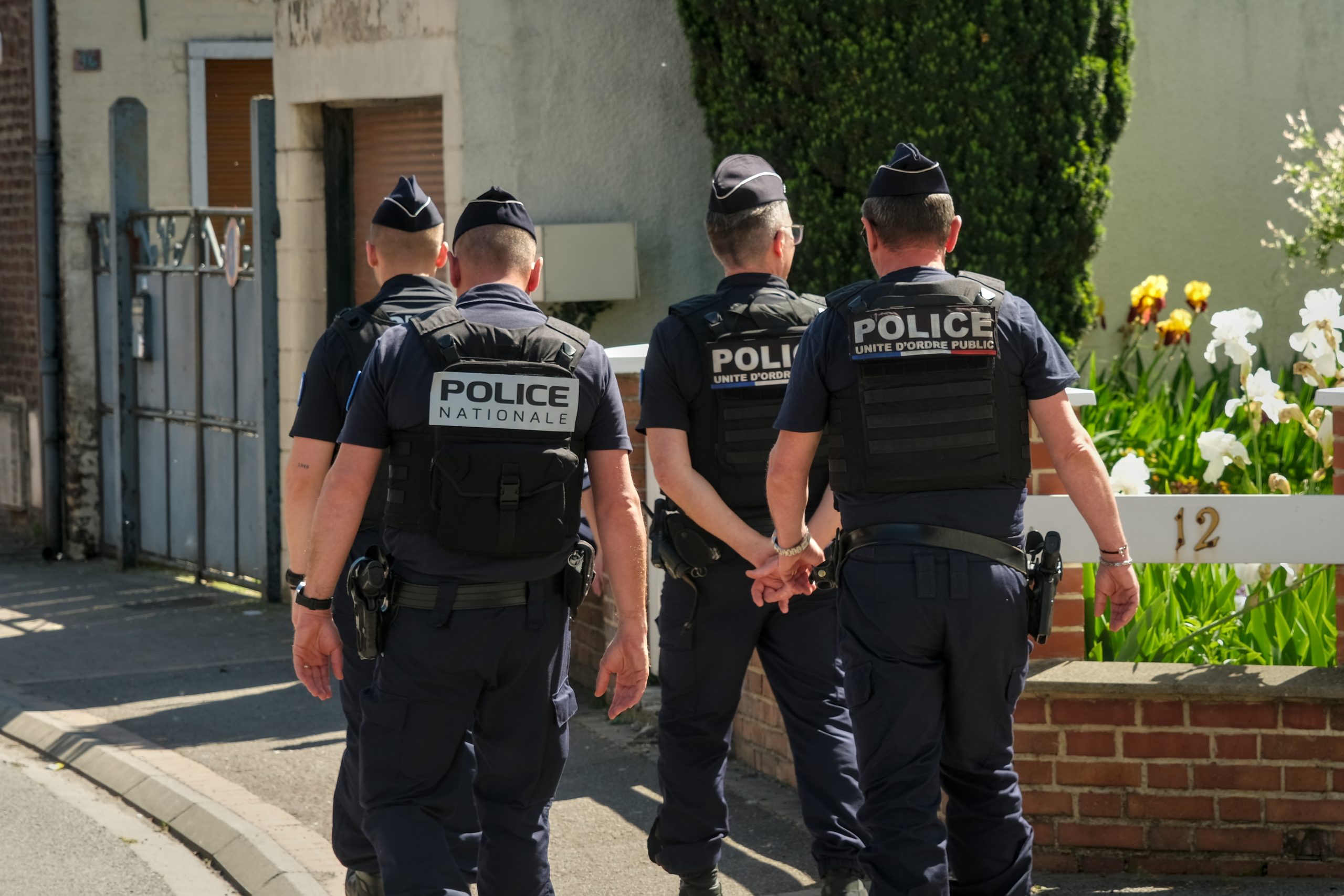 Police officers patrolling a quiet residential street in France, showing public security presence in a suburban environment.